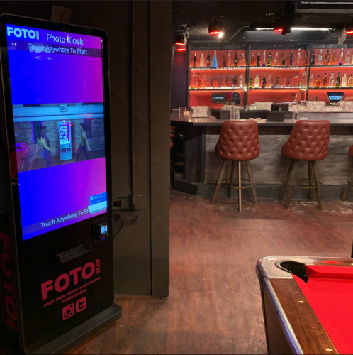 FotoATM wall-mounted photo booth kiosk installed in a bar