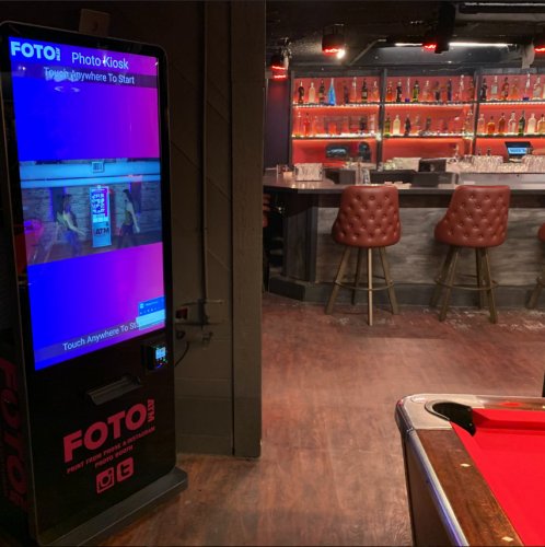 FotoATM Vista kiosk installed in a bar with pool table and ambient red lighting